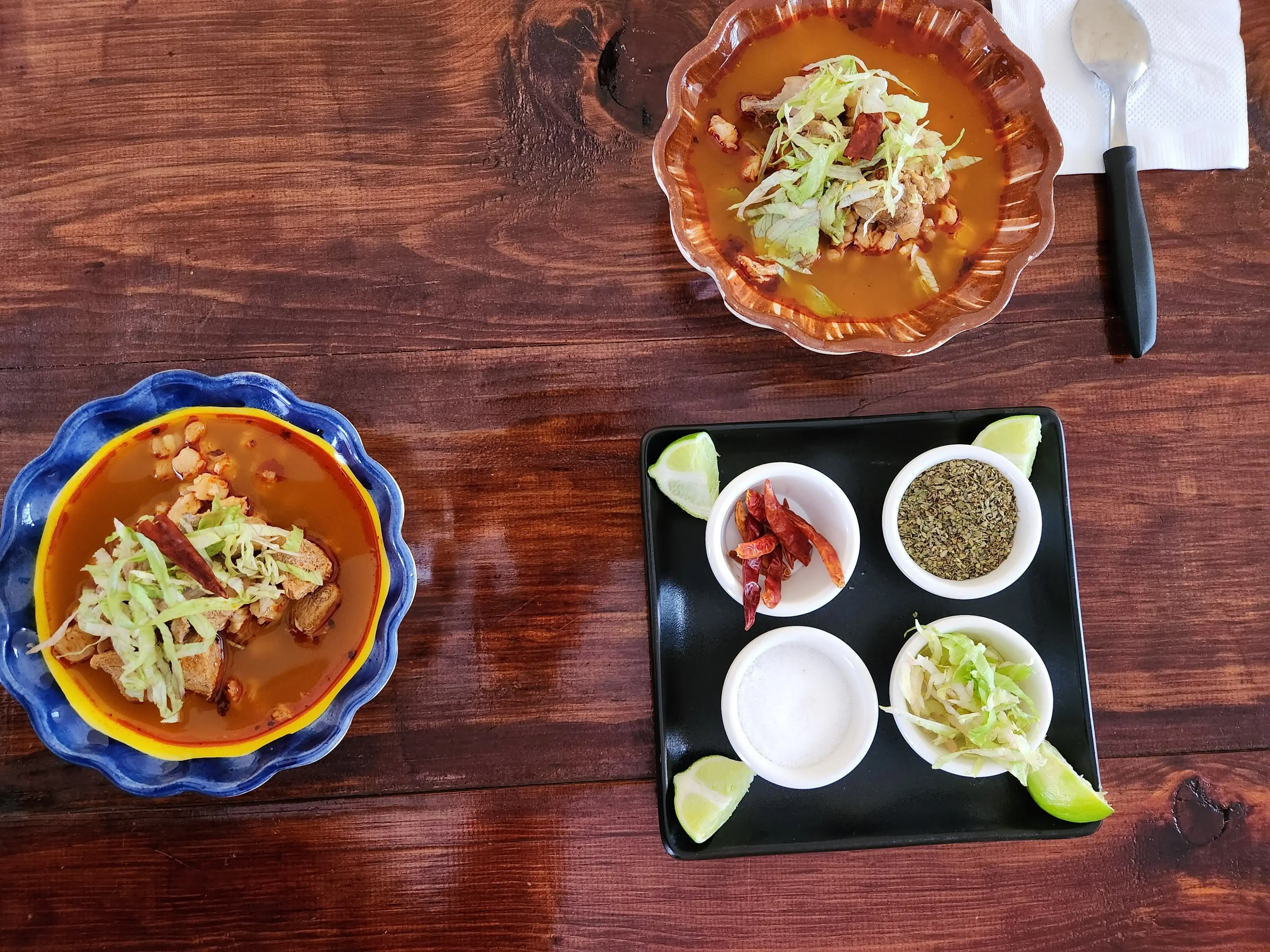 Imagen de una mesa con platos de pozole y complementos